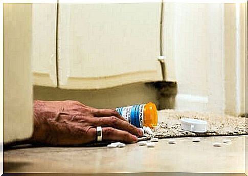 A fallen pill jar and a hand on the toilet floor.